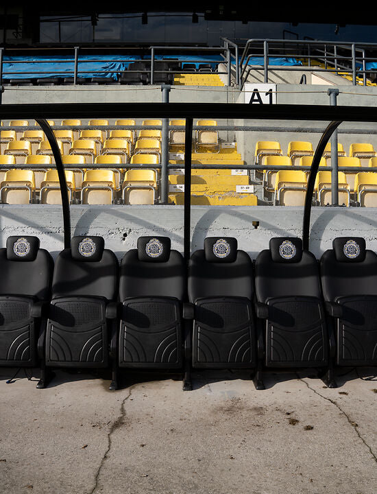 Opgeklapte busines seats met Lokeren logo in dugout